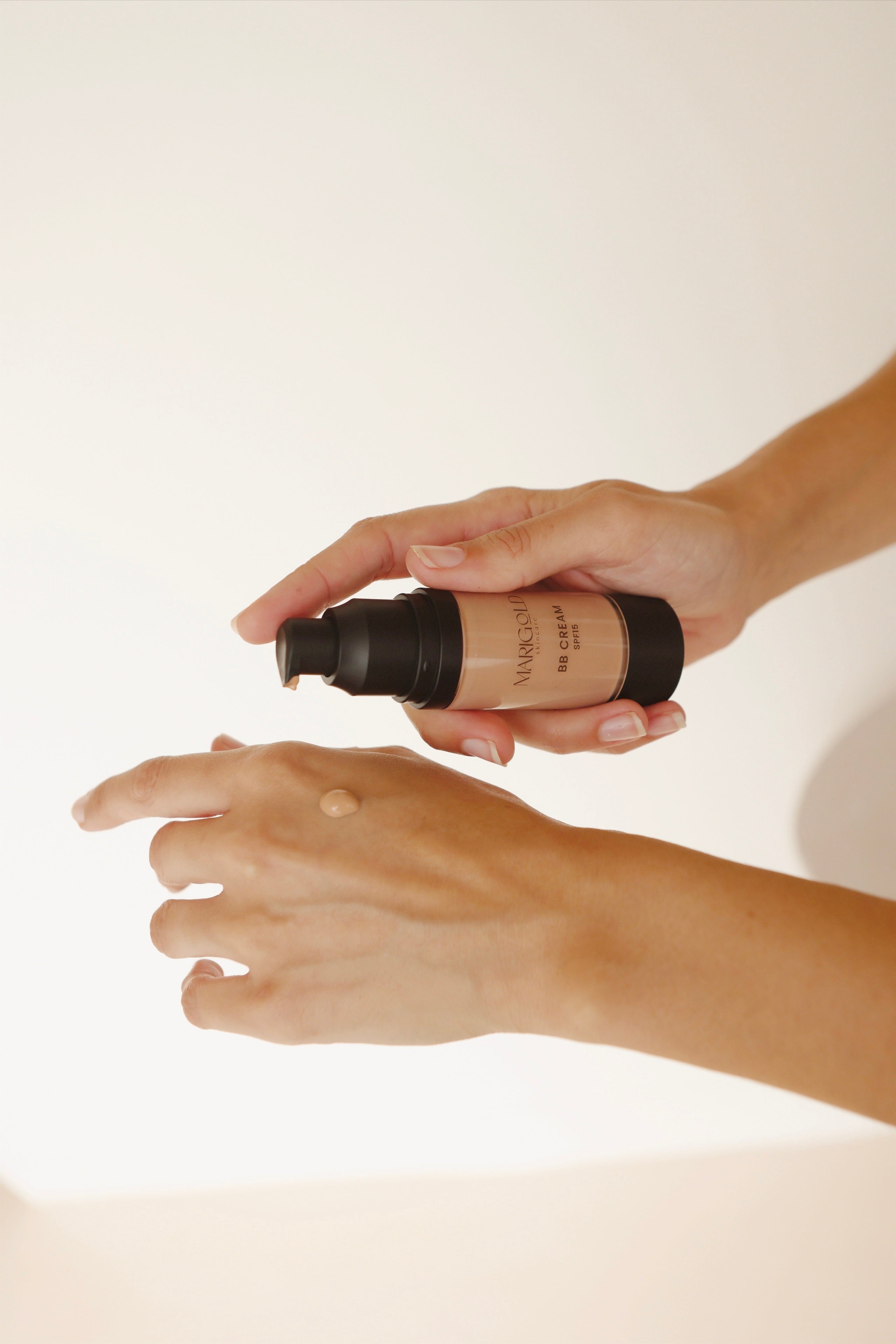 Person applying a cosmetic product to their hand on a plain background